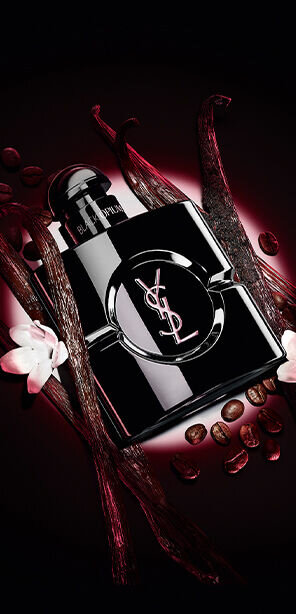 Black Opium Le Parfum bottle in glossy black, surrounded by dark vanilla pods and white jasmine.