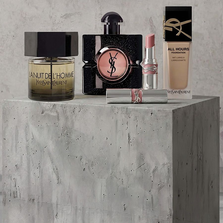 Rouges a levres YSL et crayon a levres disposes sur fond rose avec des lettres de Scrabble formant les mots "LIPS", "LIPSTICK" et "DAY"