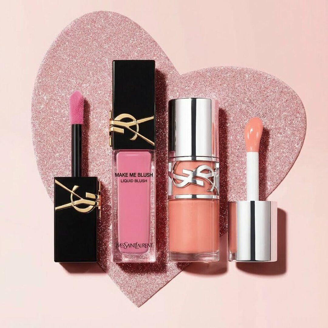 Deux blushs liquides Yves Saint Laurent aux teintes rose et corail, avec leurs applicateurs, disposes sur un coeur rose scintillant.
