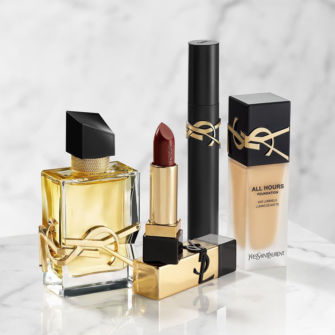 Produits de beaute YSL : parfum, rouge a levres, mascara et fond de teint sur marbre.
