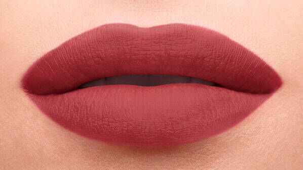 Close-up of a pair of full lips painted with a matte, deep rose-colored lipstick, with a smooth texture and subtle detail.