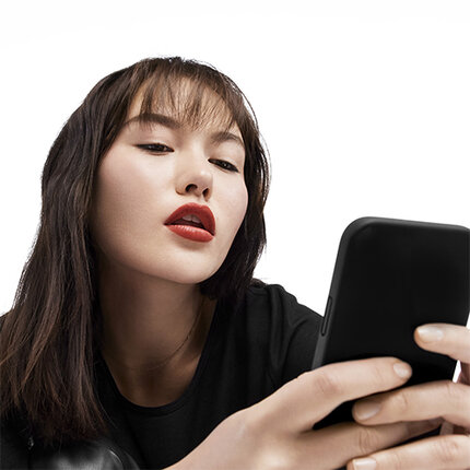 Une jeune femme avec des levres rouges regarde attentivement son telephone.