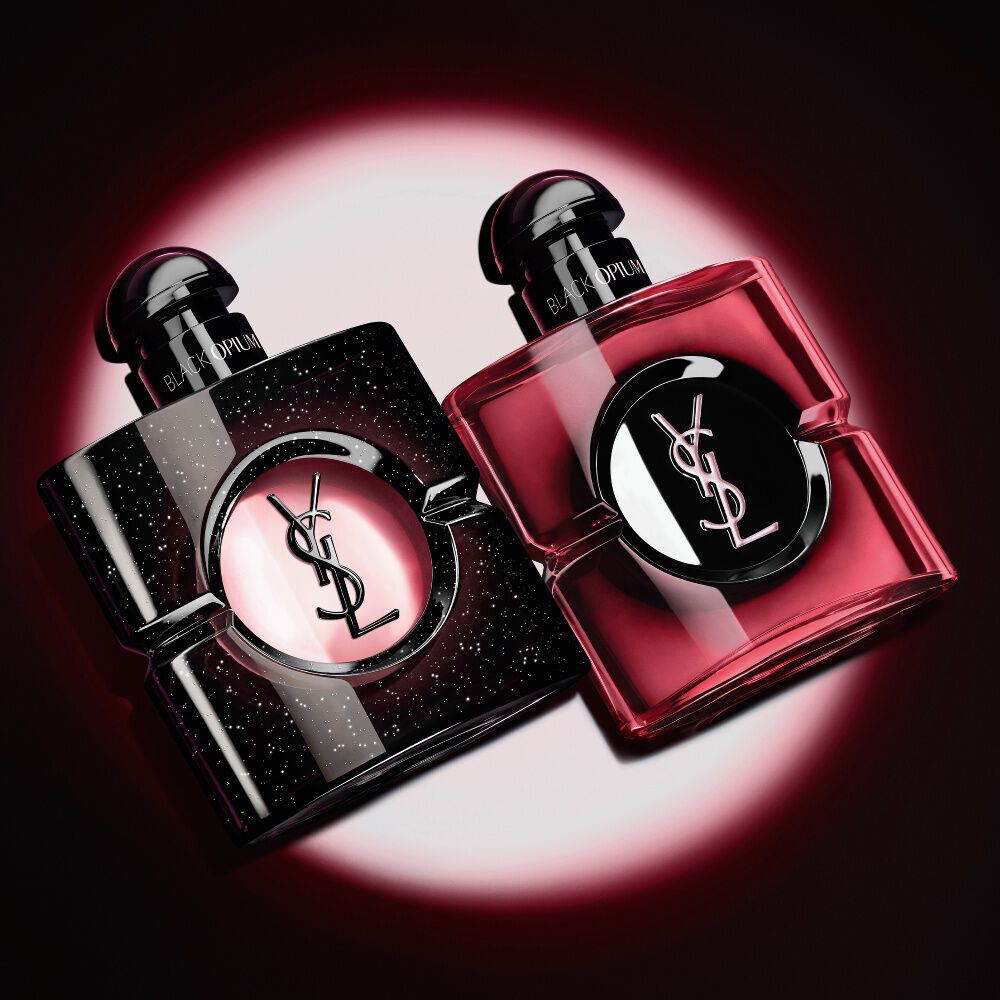 Deux flacons de parfum Black Opium d'Yves Saint Laurent illumines sur fond sombre.