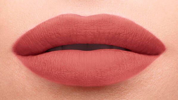 Close-up of a pair of matte, blush-colored lips slightly parted, highlighting their smooth texture.
