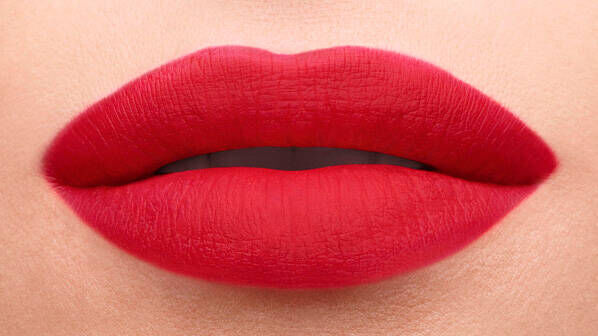Close-up of a pair of full lips painted in bright red lipstick. The skin around the lips is smooth and neutral-toned.