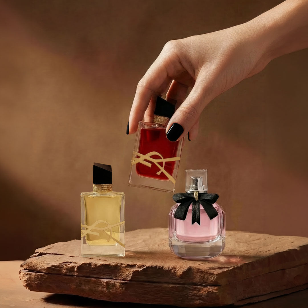 Twee YSL-parfums op een bruin stenen oppervlak.