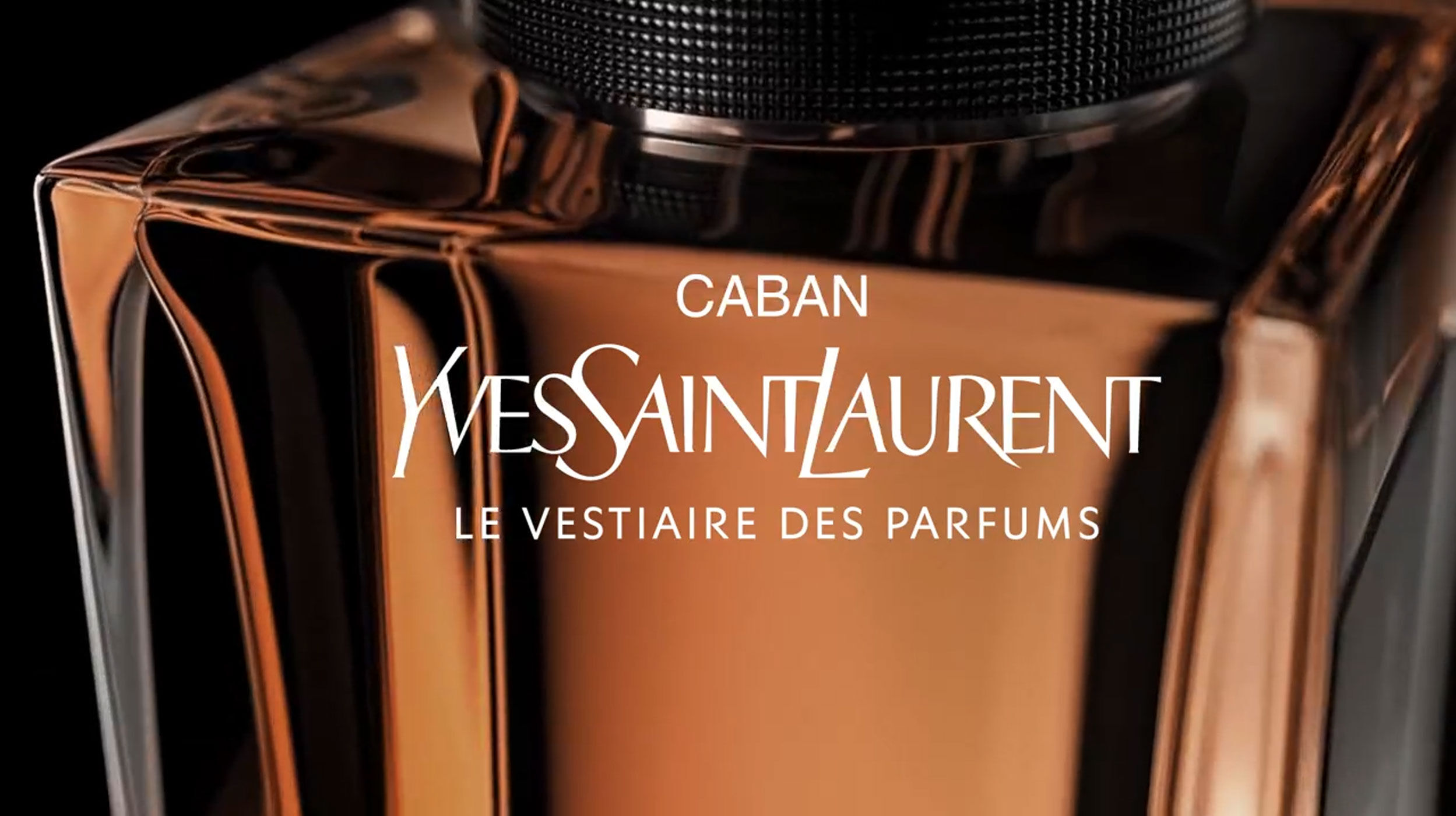 Close-up of a glossy perfume bottle labeled "Caban" by Yves Saint Laurent, showcasing elegant branding and design details.