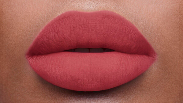 Close-up of a pair of smooth, well-defined lips painted with a matte, soft pink lipstick.