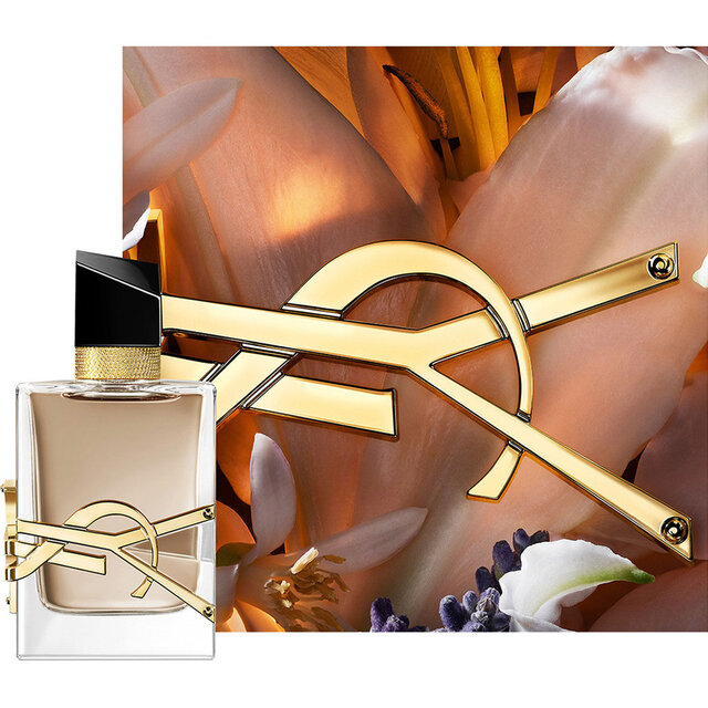Flacon LIBRE FLOWERS & FLAMES encadre de petales cremeux et du logo YSL dore dans une lumiere chaude.