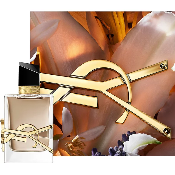 Flacon LIBRE FLOWERS & FLAMES encadre de petales cremeux et du logo YSL dore, baigne d’une lumiere chaude.