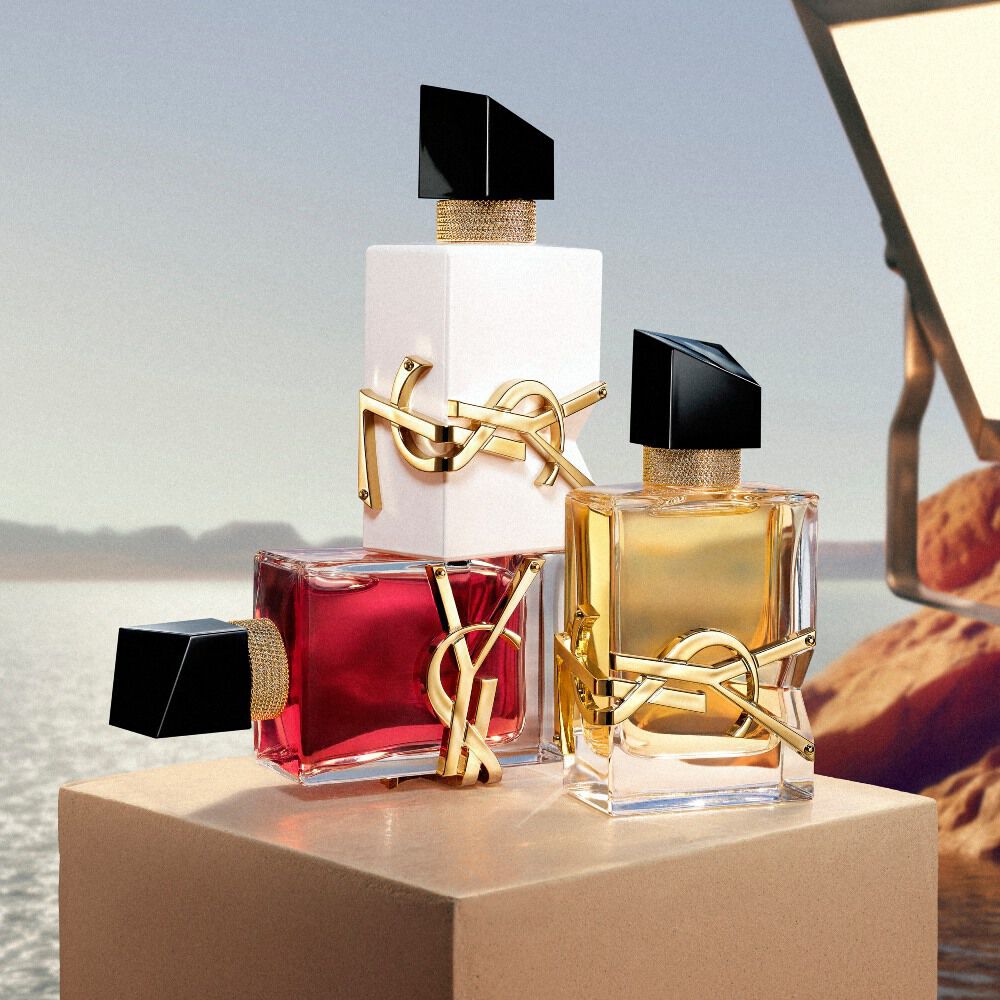 YSL-geurflacons op een sokkel tegen een woestijnlandschap.