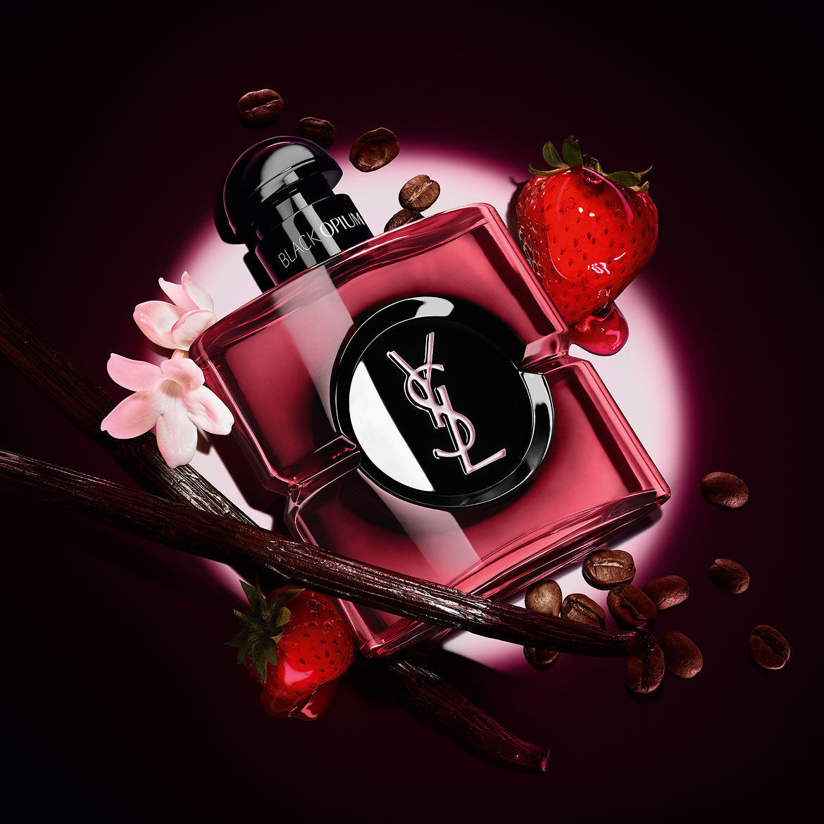 Black Opium Eau de Parfum Pink Glaze-flacon omringd door verse aardbeien, vanillestokjes, koffiebonen en jasmijn.