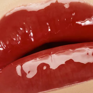 Close-up of glossy red lips with a shiny finish.