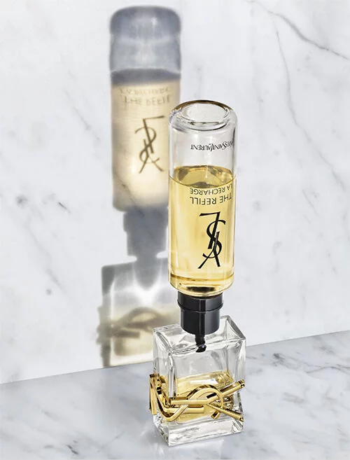 Een fles parfum op een marmeren oppervlak, met een schaduw van de fles zichtbaar.