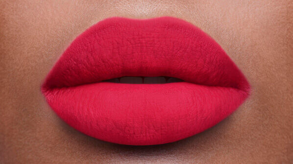 Close-up of a pair of smooth, perfectly shaped lips coated in vibrant red lipstick against a warm skin tone.