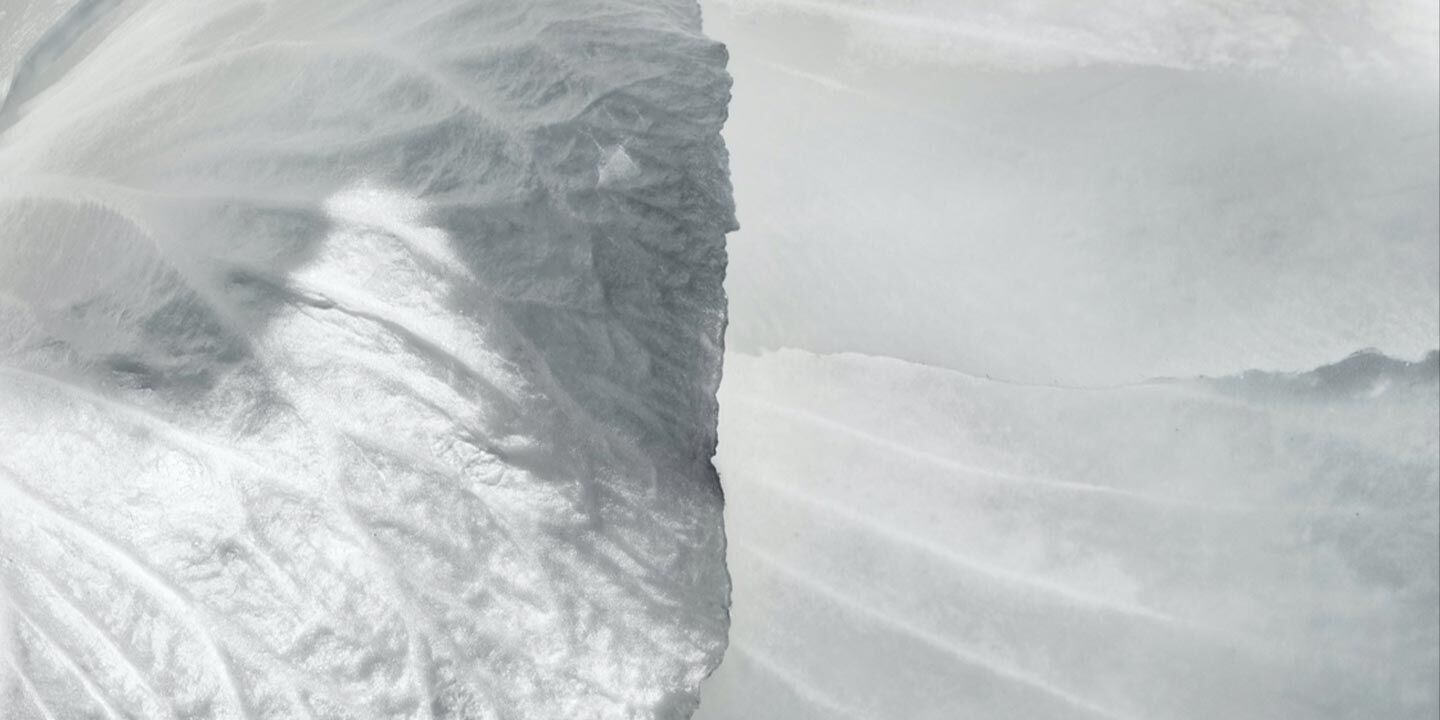 Close-up of a textured, light-colored surface with smooth and rippled patterns, creating an abstract, icy appearance.