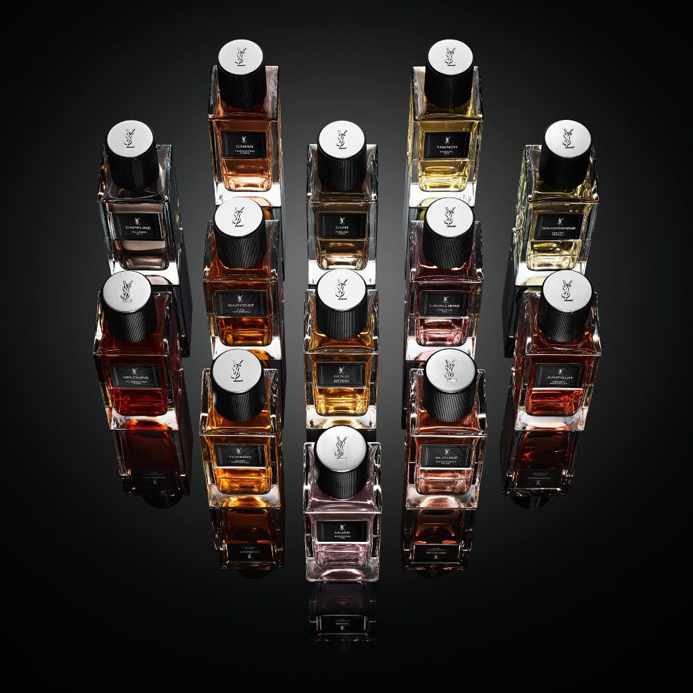 Une collection de flacons de la gamme « Le Vestiaire des Parfums » d'Yves Saint Laurent disposes en losange sur une surface noire reflechissante.