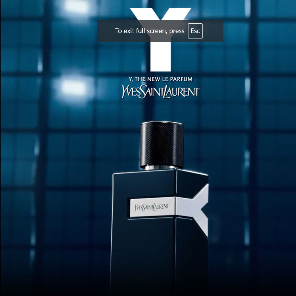 A sleek black bottle of Yves Saint Laurent's "Y" fragrance is displayed against a blurred blue background, emphasizing its modern and sophisticated design.
