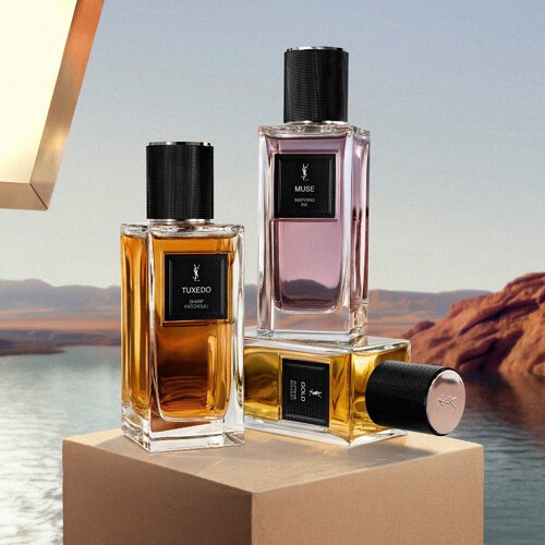 Flacons YSL Le Vestiaire des Parfums presentes sur un piedestal au bord d’un lac desertique.