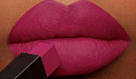 Close-up of full lips being coated with a bright pink lipstick.