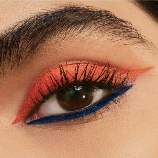 Close-up of a person's eye showcasing bold makeup with orange eyeshadow and a striking blue eyeliner.