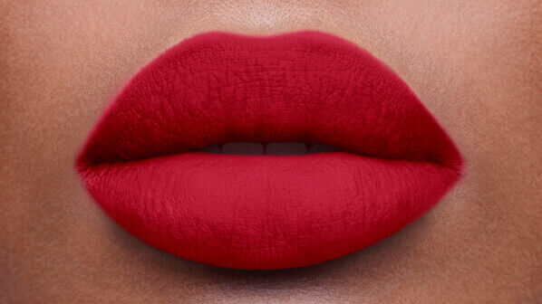 Close-up of a pair of full lips painted with vibrant red lipstick on a smooth skin tone.