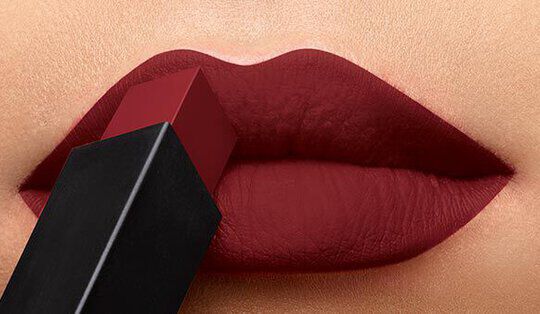 Close-up of lips applying deep red lipstick from a sleek black tube.
