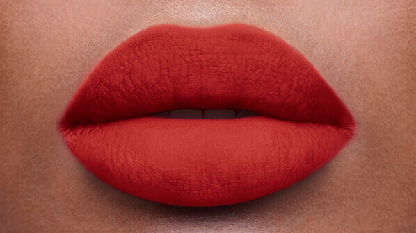 Close-up of a pair of full, vibrant red lips on a smooth skin surface.