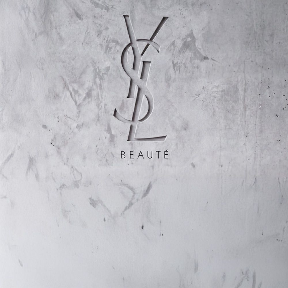 Logo YSL BEAUTE grave dans un mur en beton gris texture.