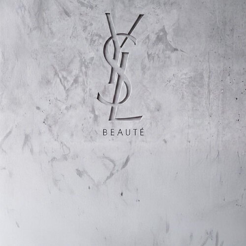 Logo YSL BEAUTE grave dans un mur en beton gris texture.