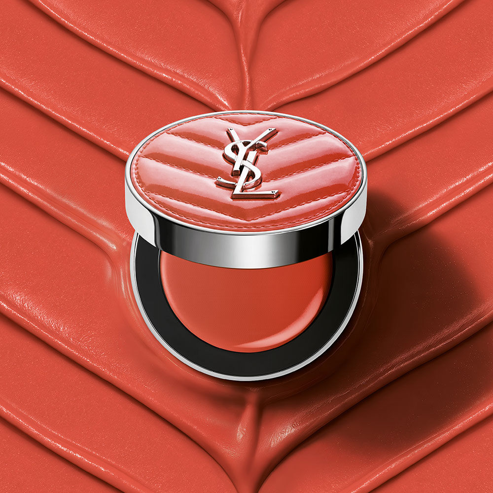 Un boitier ouvert de YSL Make Me Blush Lifted Glow Cream Blush, teinte #44 Nude Lavalliere, sur un fond creme texture rose assorti.