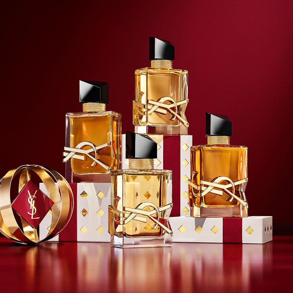 Verschillende flacons YSL LIBRE gelaagd over luxe gouden feestverpakking met exclusief patroon.