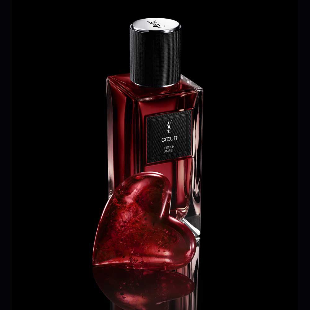 COEUR Eau de Parfum by YSL fles naast een robijnrode hartjuweel op een reflecterend zwart oppervlak.