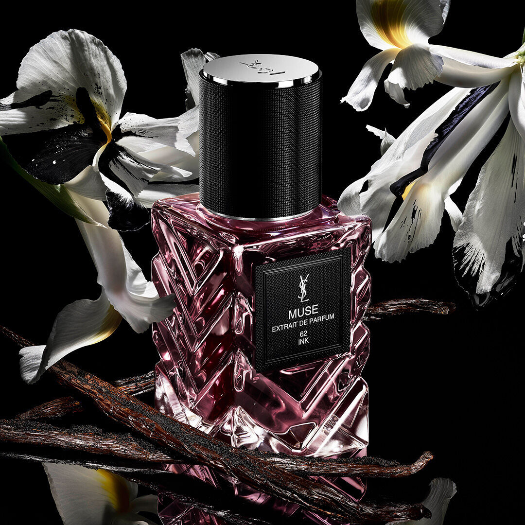 YSL Muse extrait de parfum fles met witte bloemen en vanille peulen op een zwarte achtergrond.