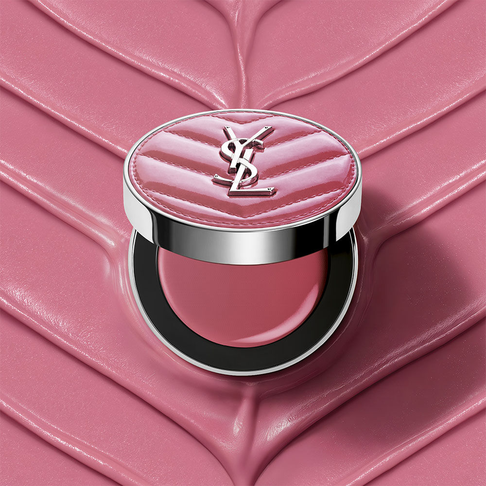 Een open YSL Make Me Blush Lifted Glow Cream Blush compact in tint #44 Nude Lavalliere op een bijpassende roze textuurcreme achtergrond.