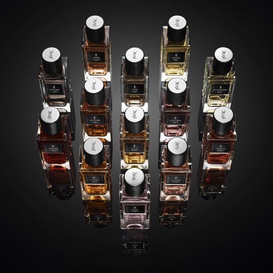 Een collectie YSL parfumflessen op een reflecterend donker oppervlak.