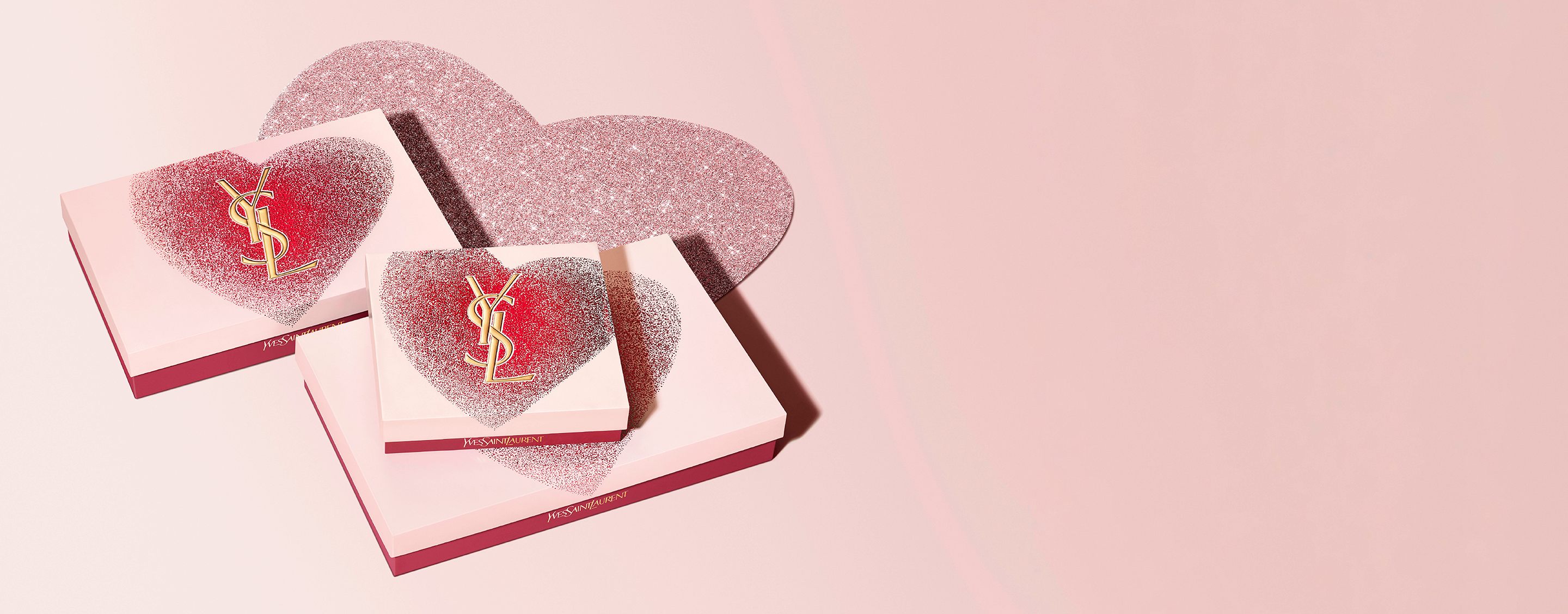 YSL Beauty Valentijnscadeausets in hartvormige dozen met gouden YSL-logo, met een glinsterend rood en roze ontwerp.