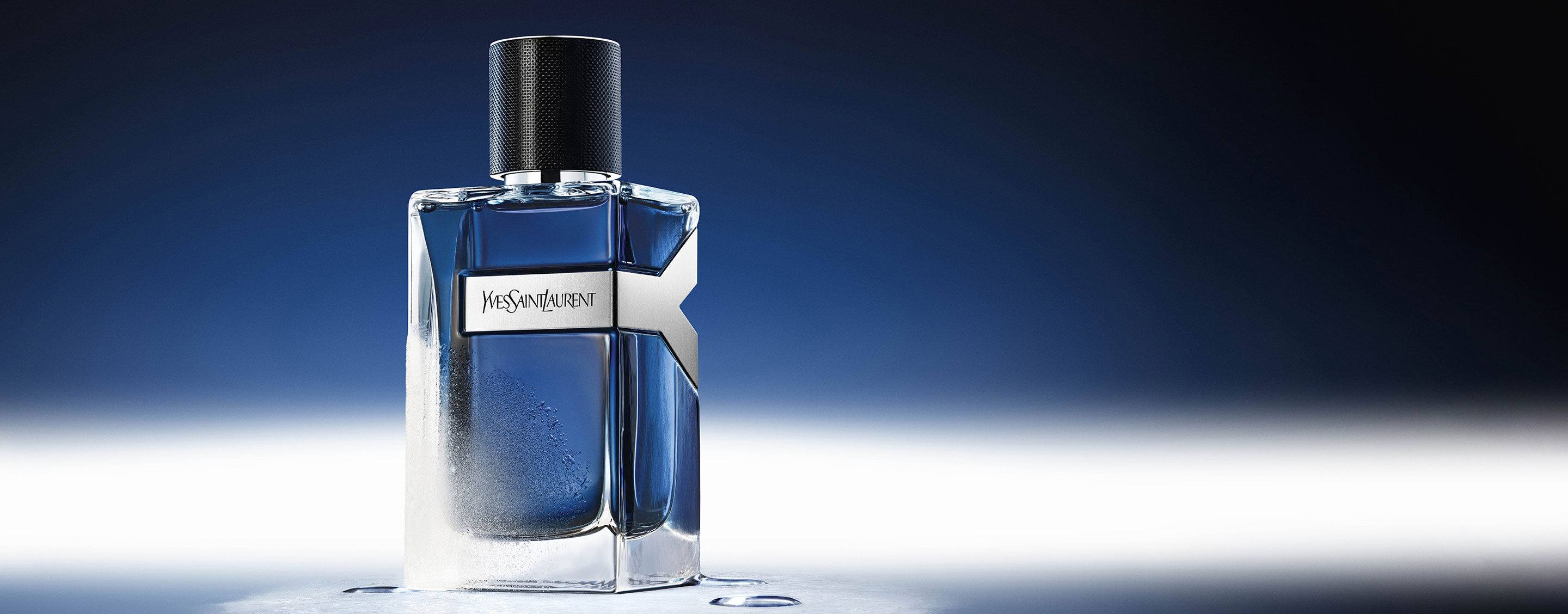 YSL Y Eau de Toilette Intense Iced Cologne 100ml flacon, matglas met waterdruppels, die een koele blauwe sfeer weerspiegelt.