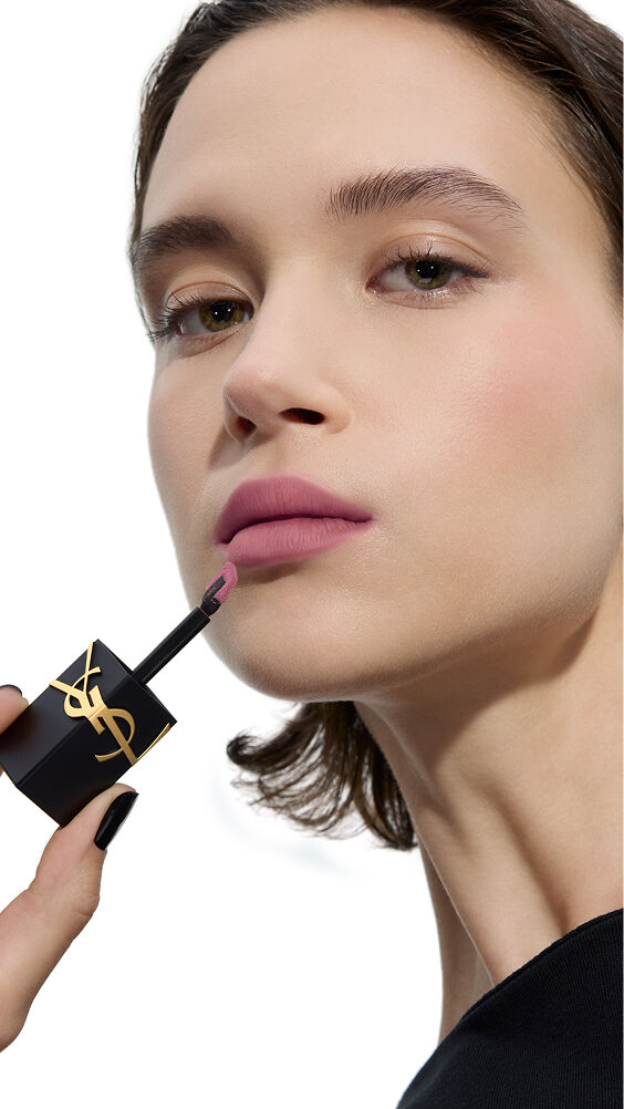 Modèle à la peau claire, appliquant une teinte mauve douce et froide de YSL THE INKS BLUR avec le pinceau-applicateur.