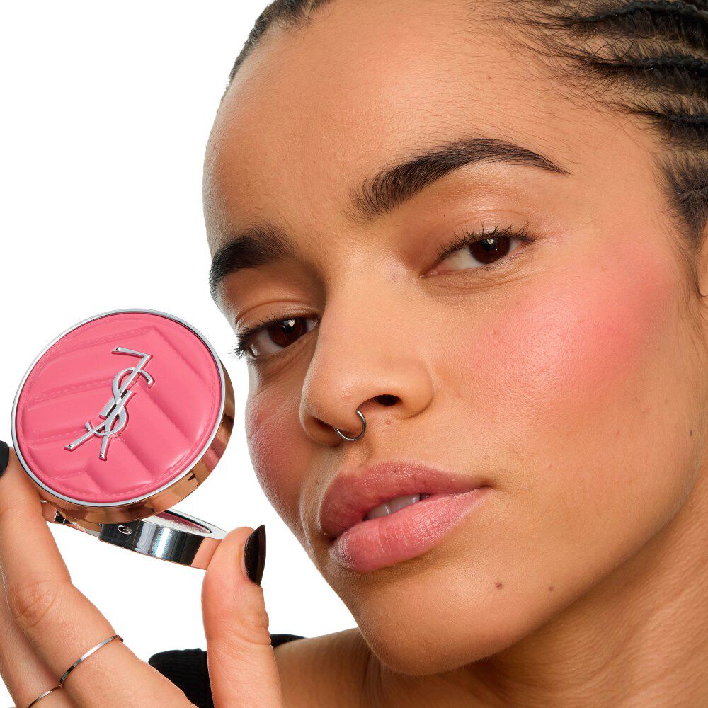 Close-up van een model dat de YSL Make Me Blush Lifted Glow Cream Blush vasthoudt, met een stralende, opgetilde gloed op haar jukbeenderen. mieux
