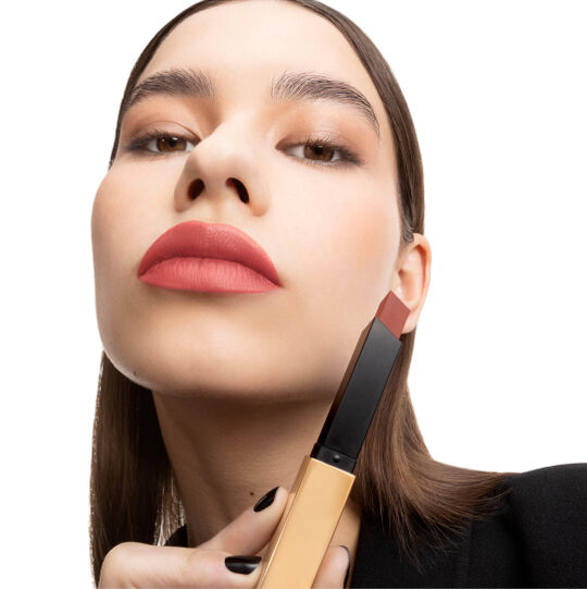 Main tenant un étui YSL noir et or fermé.