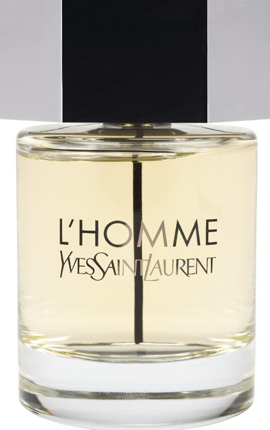 Un flacon de parfum Yves Saint Laurent L'Homme avec un corps en verre transparent, un jus ambré clair et un large capot hexagonal argenté.