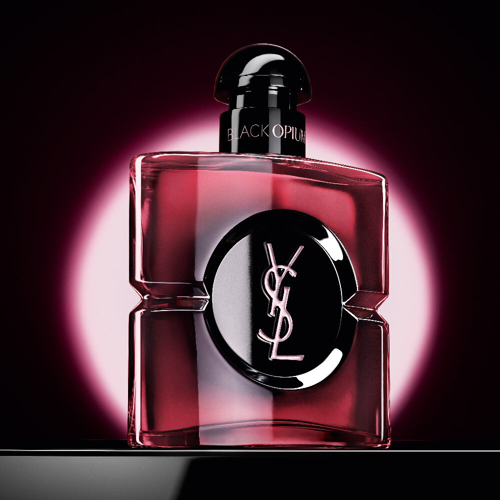 Black
                Opium Eau de Parfum Pink Glaze-fles met een roze cirkelvormige gloed op een donkere
                achtergrond.
