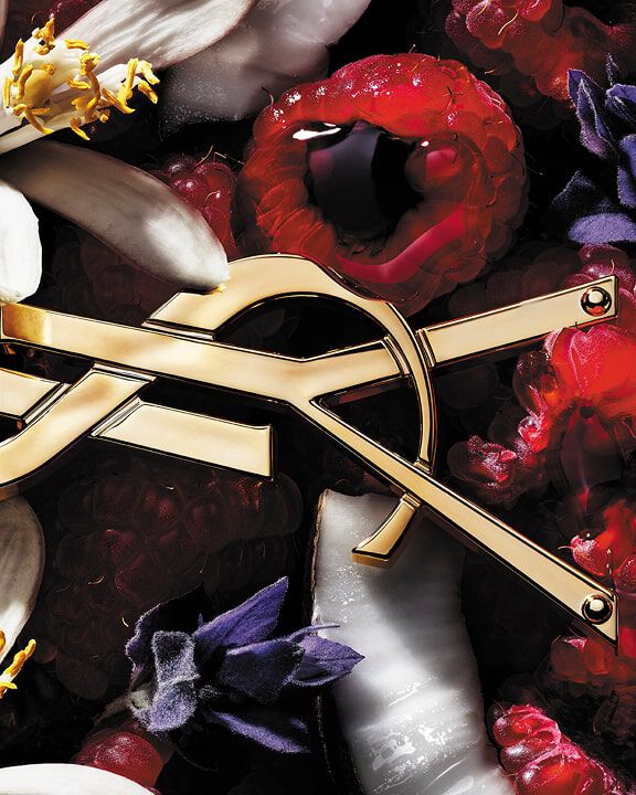 YSL-logo omringd door frambozen, witte en paarse bloemen en kokosnoot.