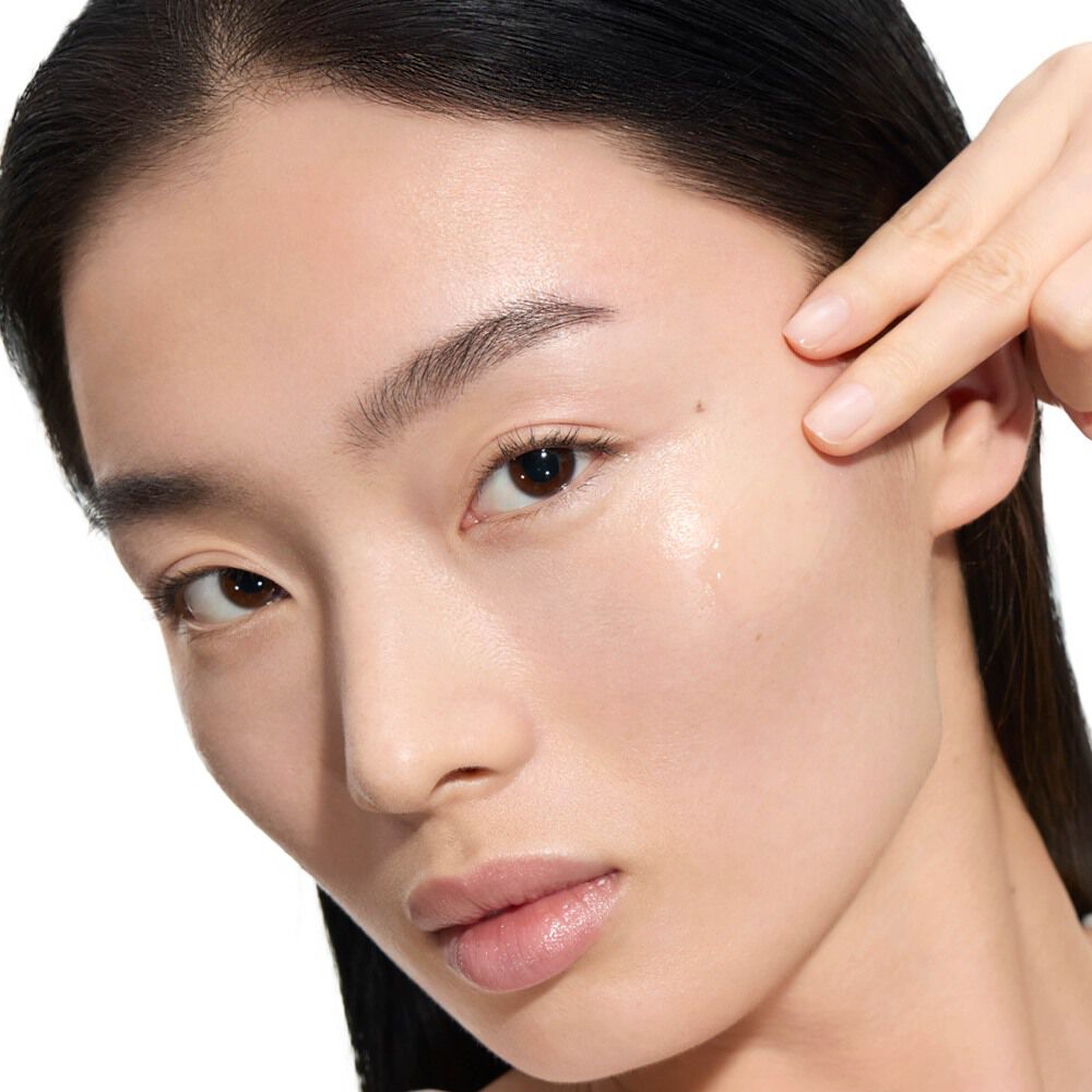 Wen, YSL Beauty-model, met een lichte huid, brengt een druppel Pure Shots Youth Reload Serum aan op haar wang.