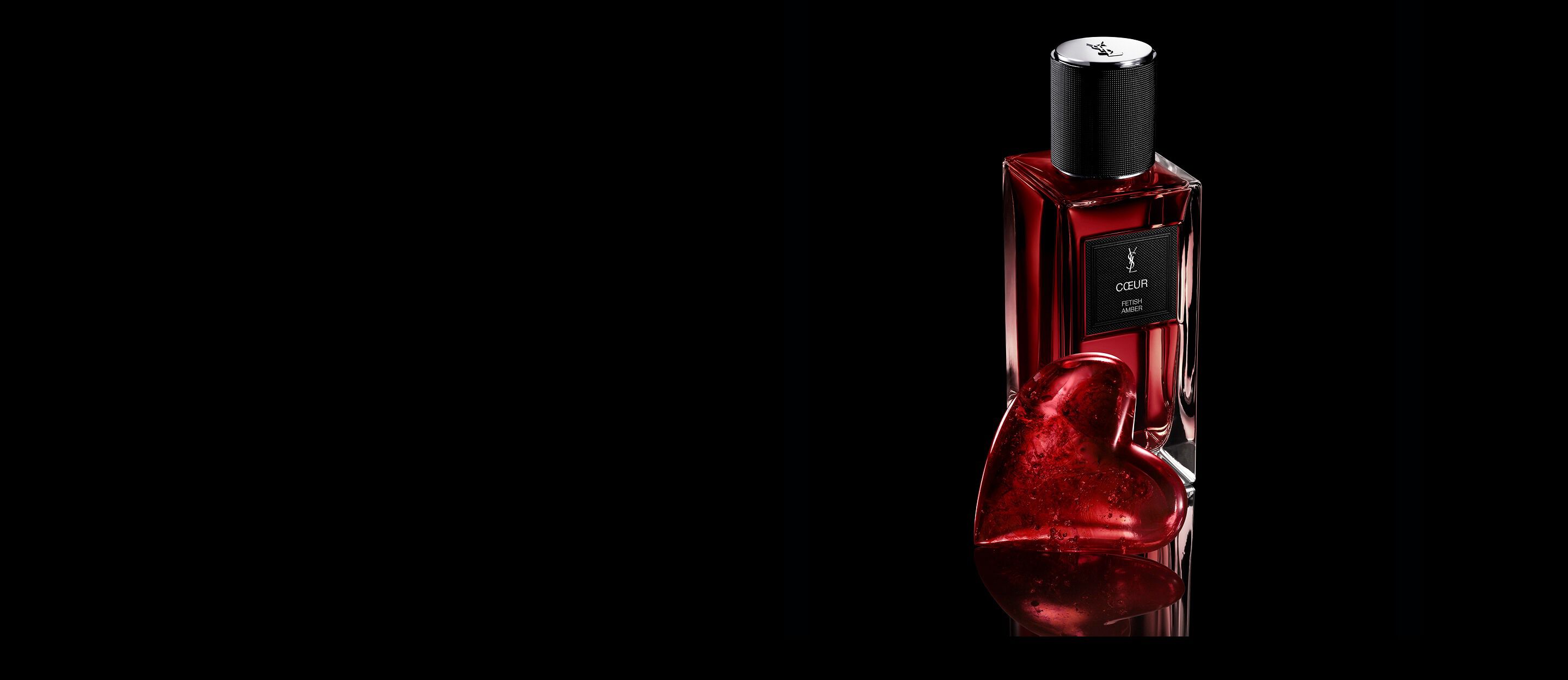 Flacon van CŒUR Eau de Parfum van YSL
naast een robijnrood hartjuweel op een
reflecterend zwart oppervlak.