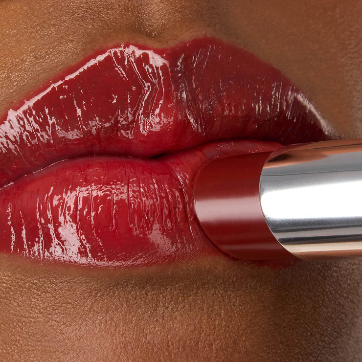 Close-up van de YSL LOVESHINE Lipstick in de kleur Berry Crush, tint 219, die wordt aangebracht op de glanzende, felrode lippen van model Zahara.