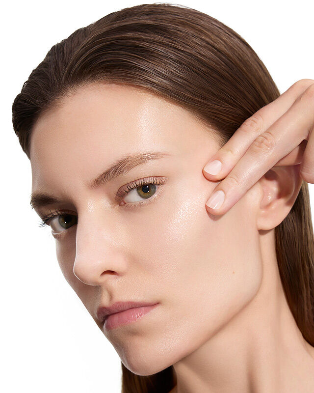 Marije, modèle YSL Beauty, avec une peau claire, touchant doucement sa joue, montrant une peau lisse après l'application de la lotion.